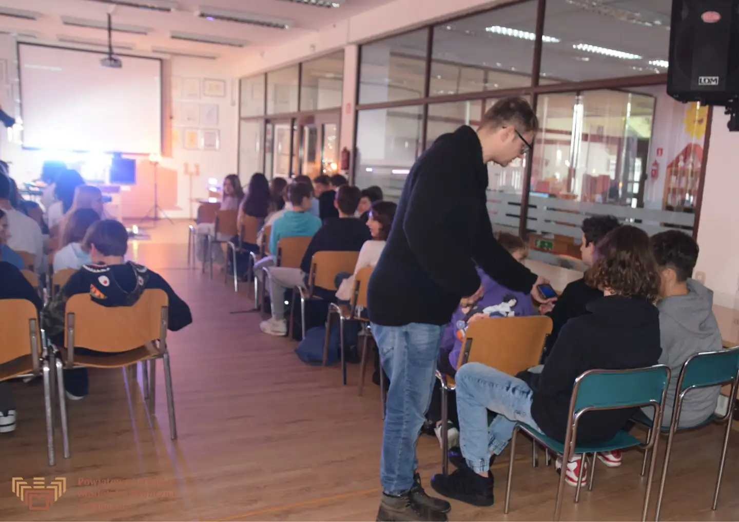 Zdjęcie zostało zrobione w Czytelni olkuskiej Biblioteki. Przedstawia Jacka Pełkę rozmawiającego z licznie zgromadzoną młodzieżą.